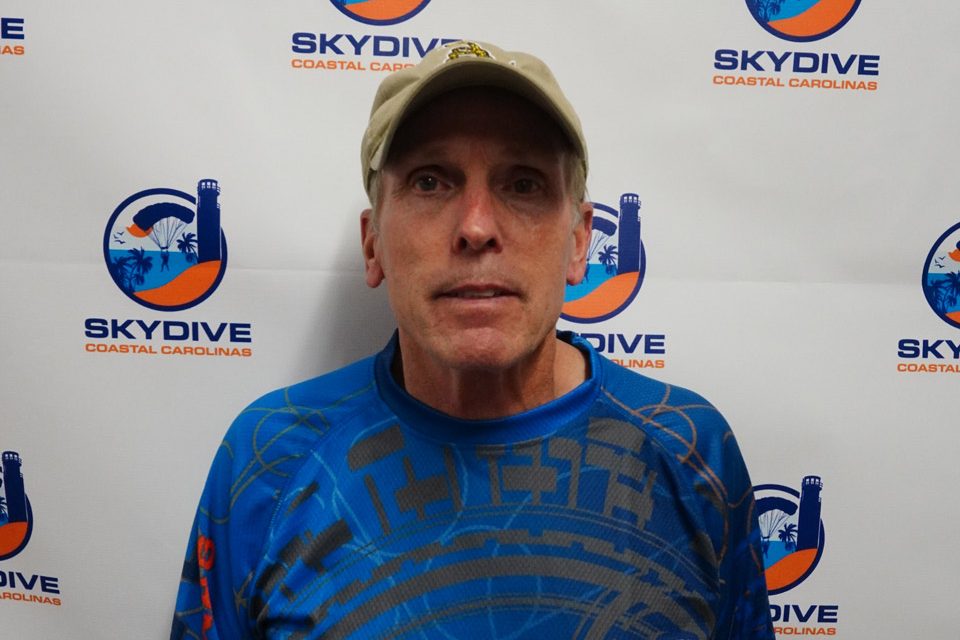 Headshot of of Skydive Coastal Carolinas skydiving instructor Robert Mehl in front of backdrop with Skydive Coastal Carolina Logo