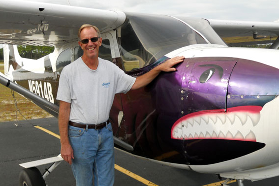 Skydive Coastal Carolinas owner Brian Strong poses next to Cessna 182 with a purple shark painted on it