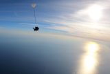 Silhouette of tandem skydiving pair over the ocean
