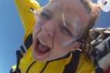 Freckled female tandem skydiving student yelling in freefall