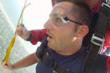 Tandem skydiving student with awestruck expression takes in the view from beneath the parachute