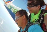 Tandem skydiving student with unsure expression and female tandem skydiving instructor as they exit the Cessna-182