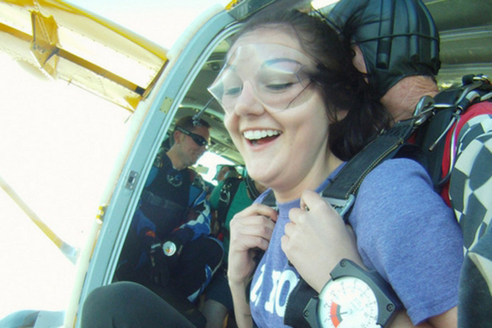 Brightly smiling tandem student looks down just before exiting aircraft