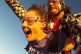 Close up of tandem skydiving student enjoying freefall with a smiling tandem instructor behind her