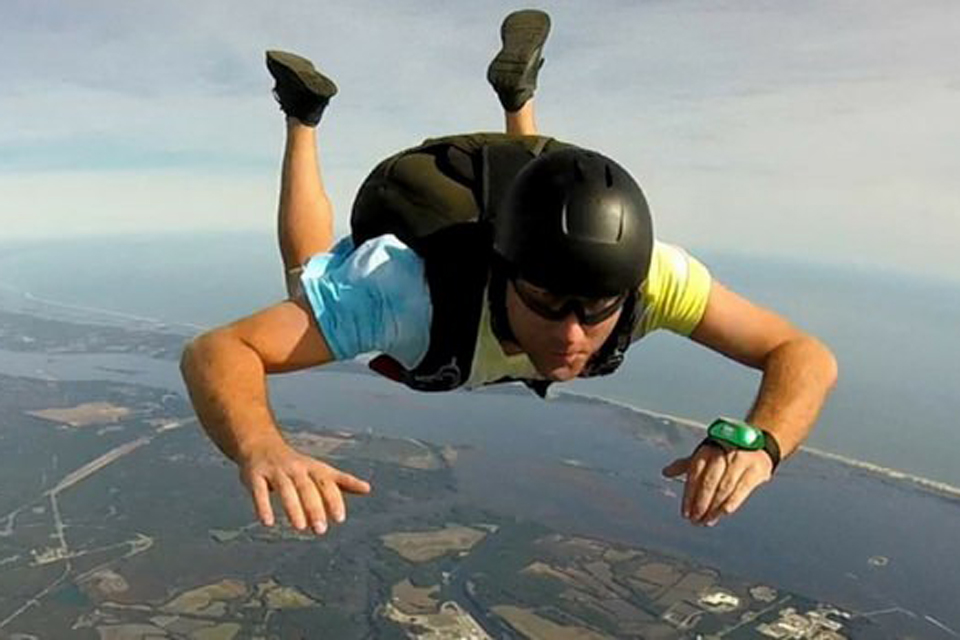 Accelerated freefall student with a serious expression skydiving over the coast of Oak Island, NC