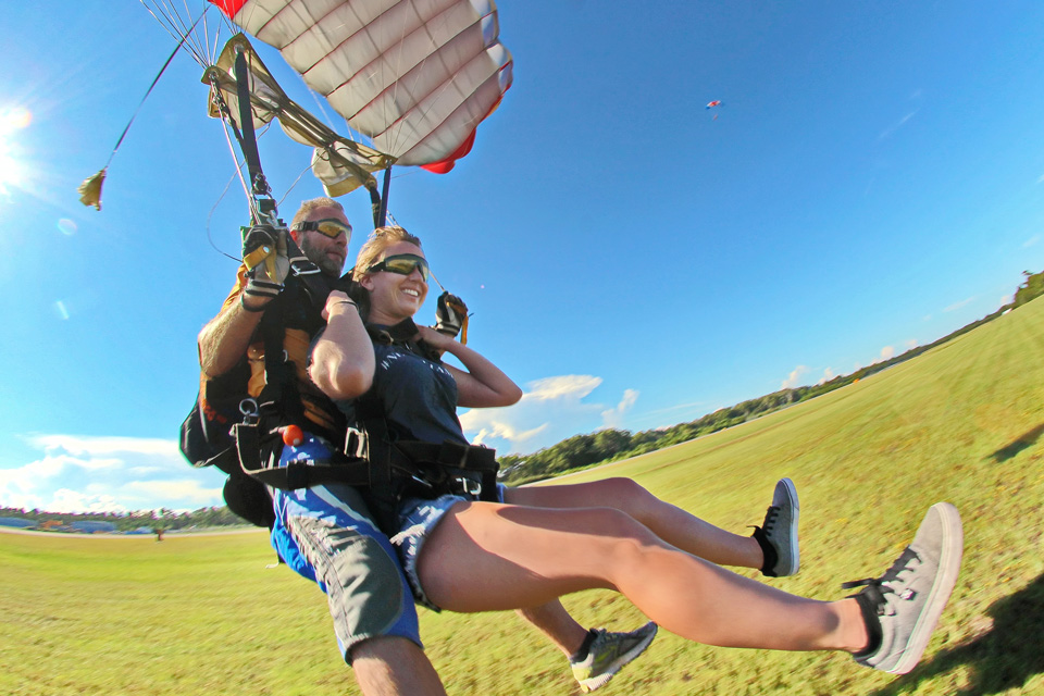 Smiling tandem student and instructor prepare to slide in a landing