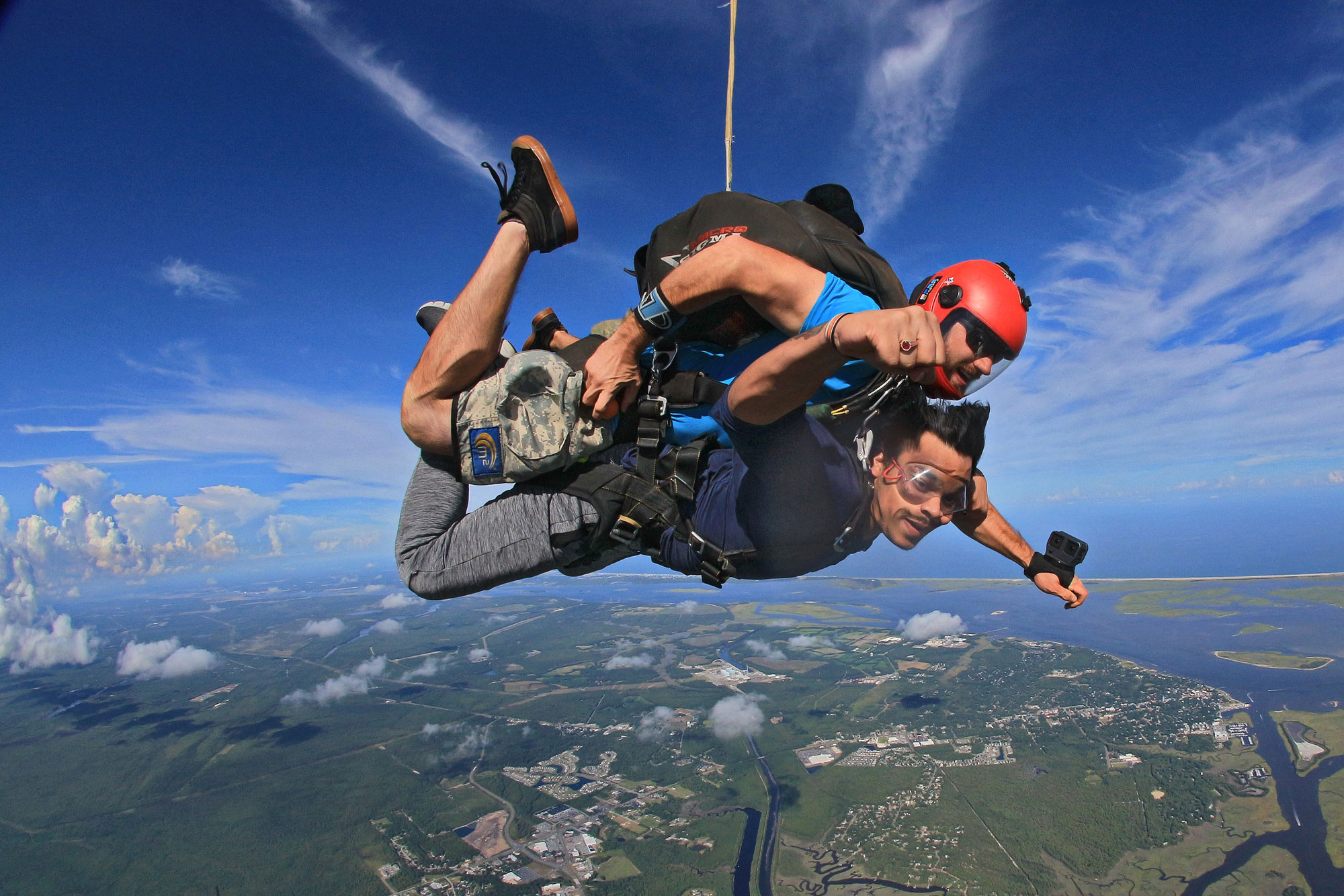 Tandem skydiving instructor with hand on orange deployment handle and tandem skydiving student in freefall near Myrtle Beach