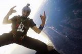 Exuberant licensed skydiver in a gray helmet holds up both hands with the rock on gesture