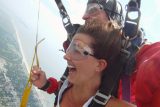 Elated tandem skydiving student enjoys the ride beneath the parachute