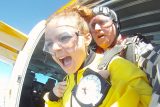 Young female tandem skydiving student lets out a yell before exiting the aircraft
