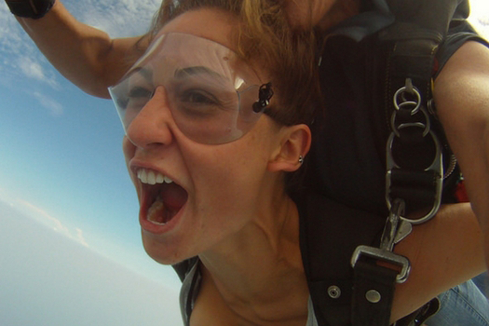 Female tandem skydiving student wearing clear goggles and yelling in freefall